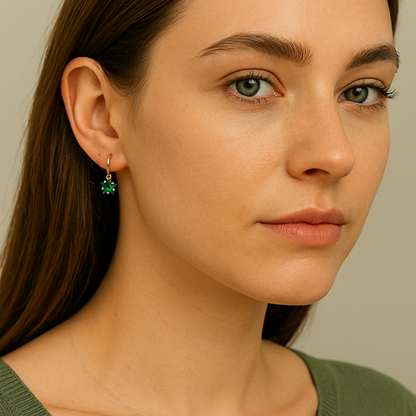 Close-up of a woman wearing green star hoop earrings against a neutral background