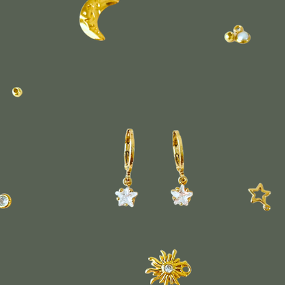 Gold earrings with star and moon designs on a dark gray background