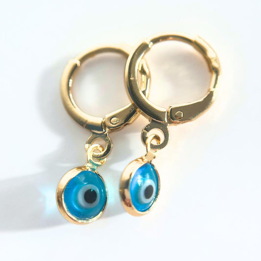 Gold plated hoop earrings with glass blue evil eye charms on a white background