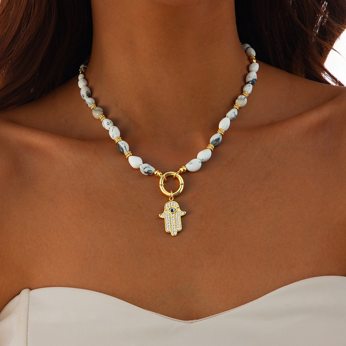 A women wear a natural howlite gemstone Necklace with a CZ Hamsa Hand Evil Eye Pendant
