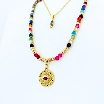Colorful beaded necklace with a gold pendant stack with a blue glass bead chain necklace on a white background