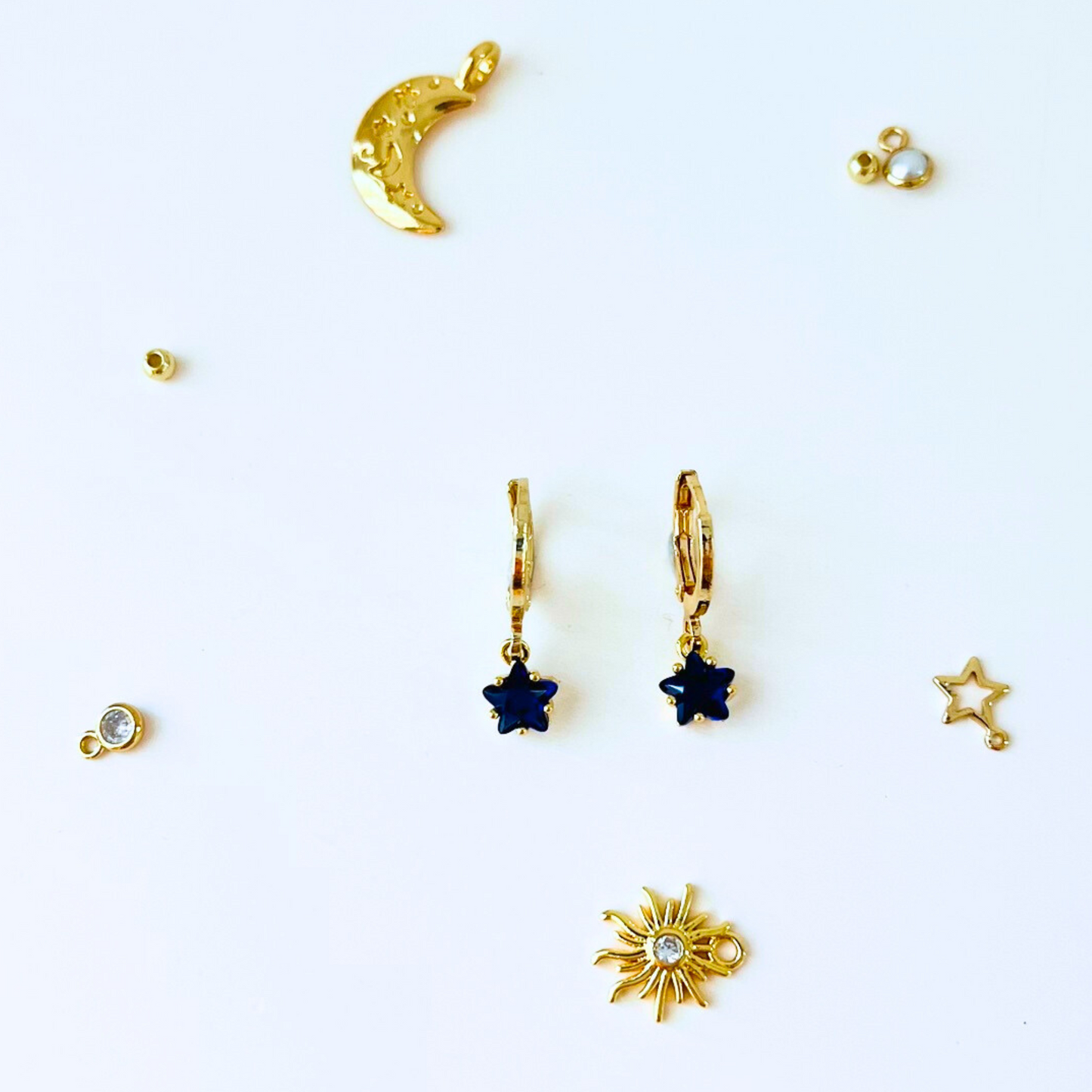 September Birthstone Sapphire CZ Star Hoop Earrings with Collection of gold  jewelry pieces on a white background