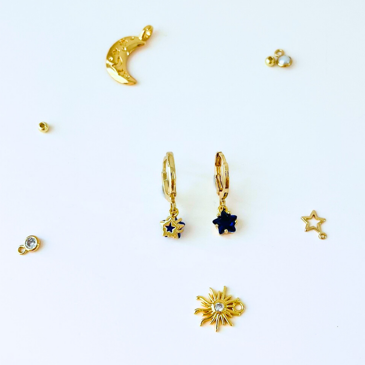 September Birthstone Sapphire CZ Star Hoop Earrings with Collection of gold jewelry pices on a white background