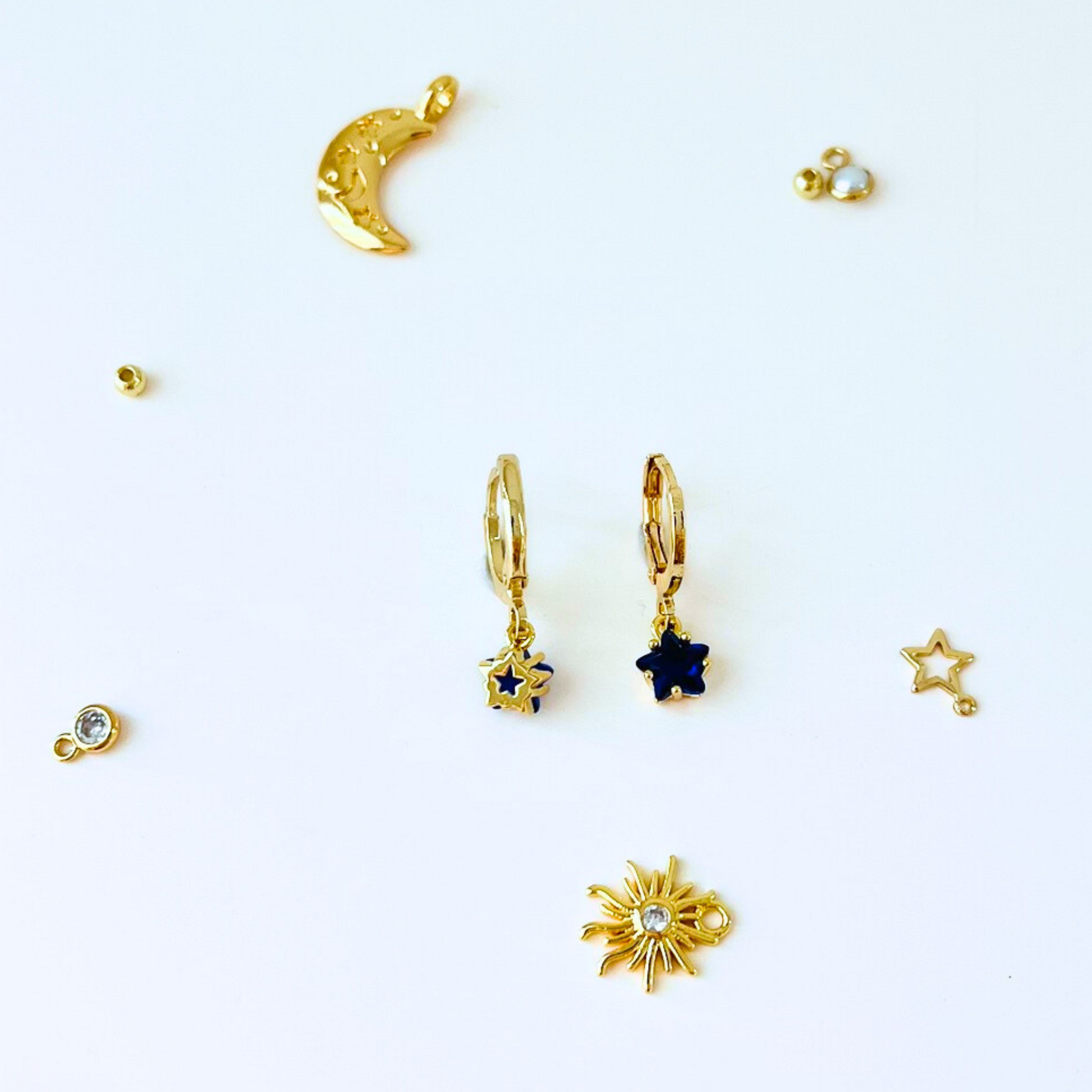 September Birthstone Sapphire CZ Star Hoop Earrings with Collection of gold jewelry pices on a white background