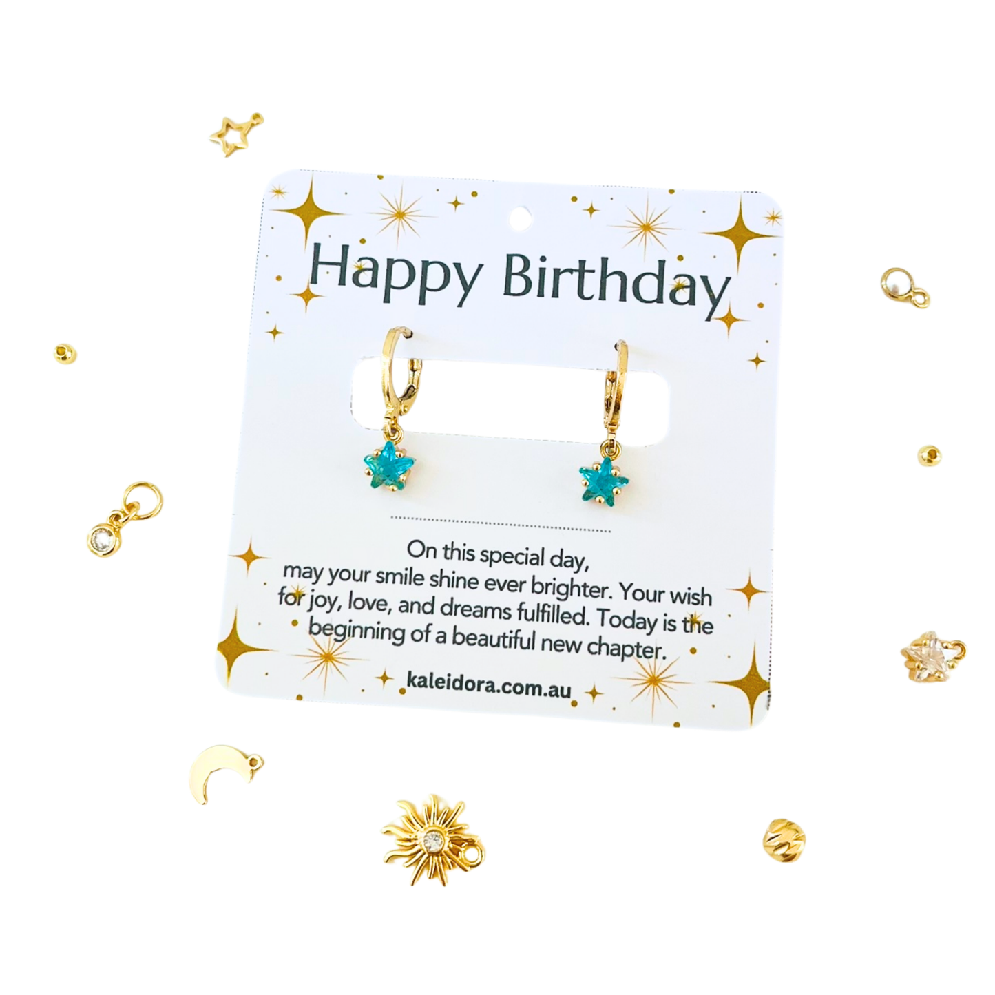 Gold earrings with blue stones on a 'Happy Birthday' card with decorative elements.