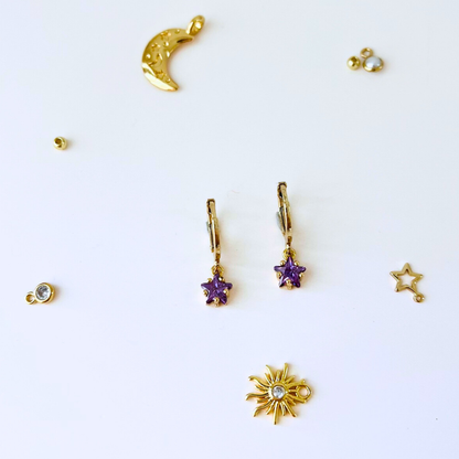 Collection of gold and purple jewelry charms on a white background