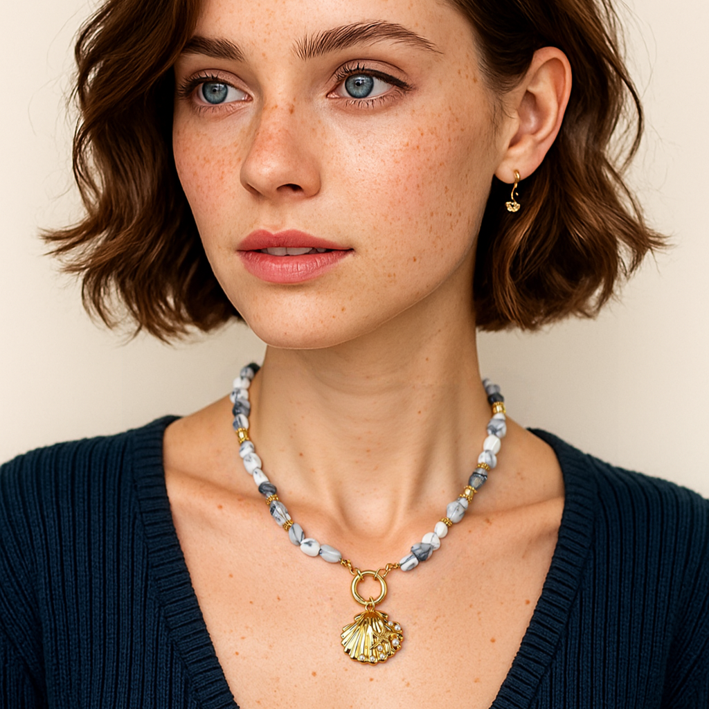 Woman wearing a necklace with a shell pendant against a neutral background