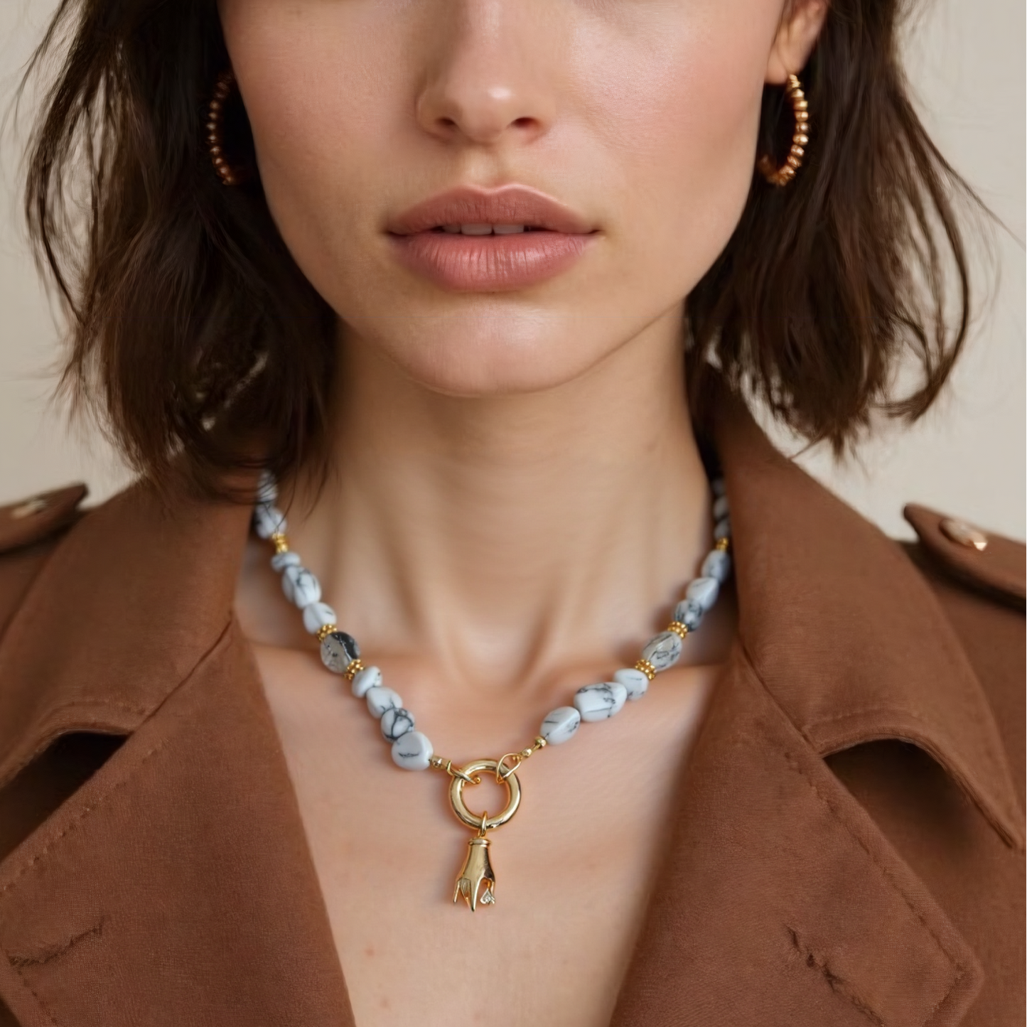 Woman wearing a natural howlite gemstone necklace with Gold Plated Hand Heart CZ Pendant against a neutral background