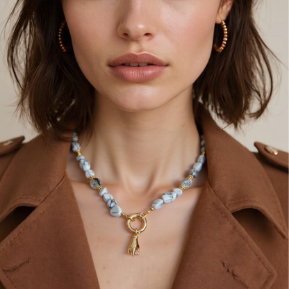 Woman wearing a natural howlite gemstone necklace with Gold Plated Hand Heart CZ Pendant against a neutral background