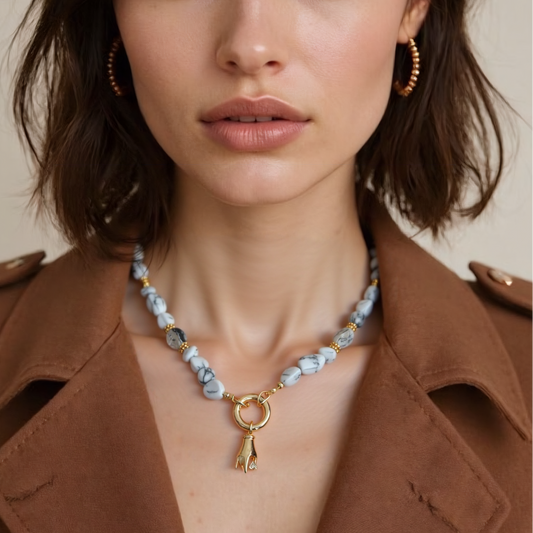 Woman wearing a natural howlite gemstone necklace with Gold Plated Hand Heart CZ Pendant against a neutral background