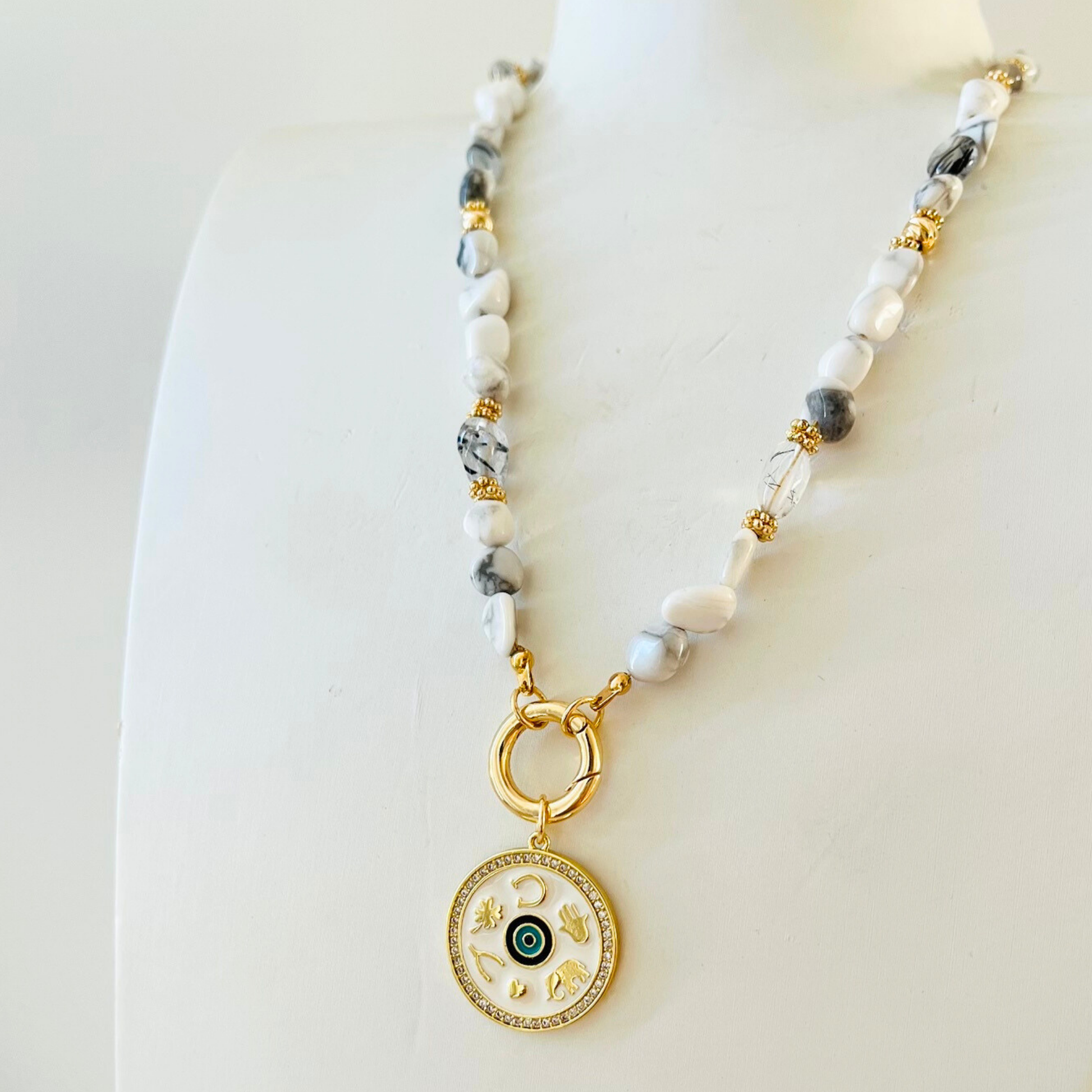 natural howlite beaded Necklace  and decorative Gold Plated Symbols pendant on a white background