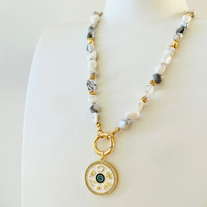 natural howlite beaded Necklace  and decorative Gold Plated Symbols pendant on a white background