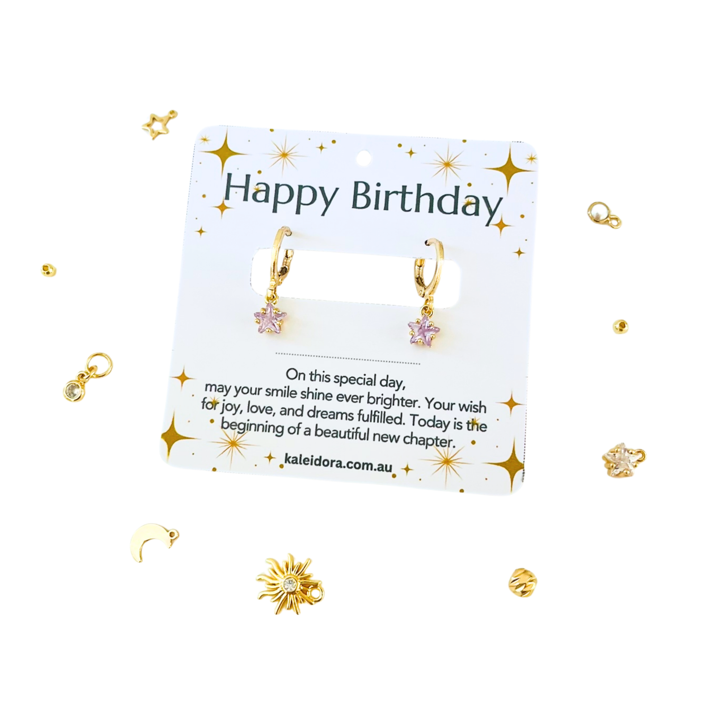 Gold earrings on a 'Happy Birthday' card with decorative elements on a white background