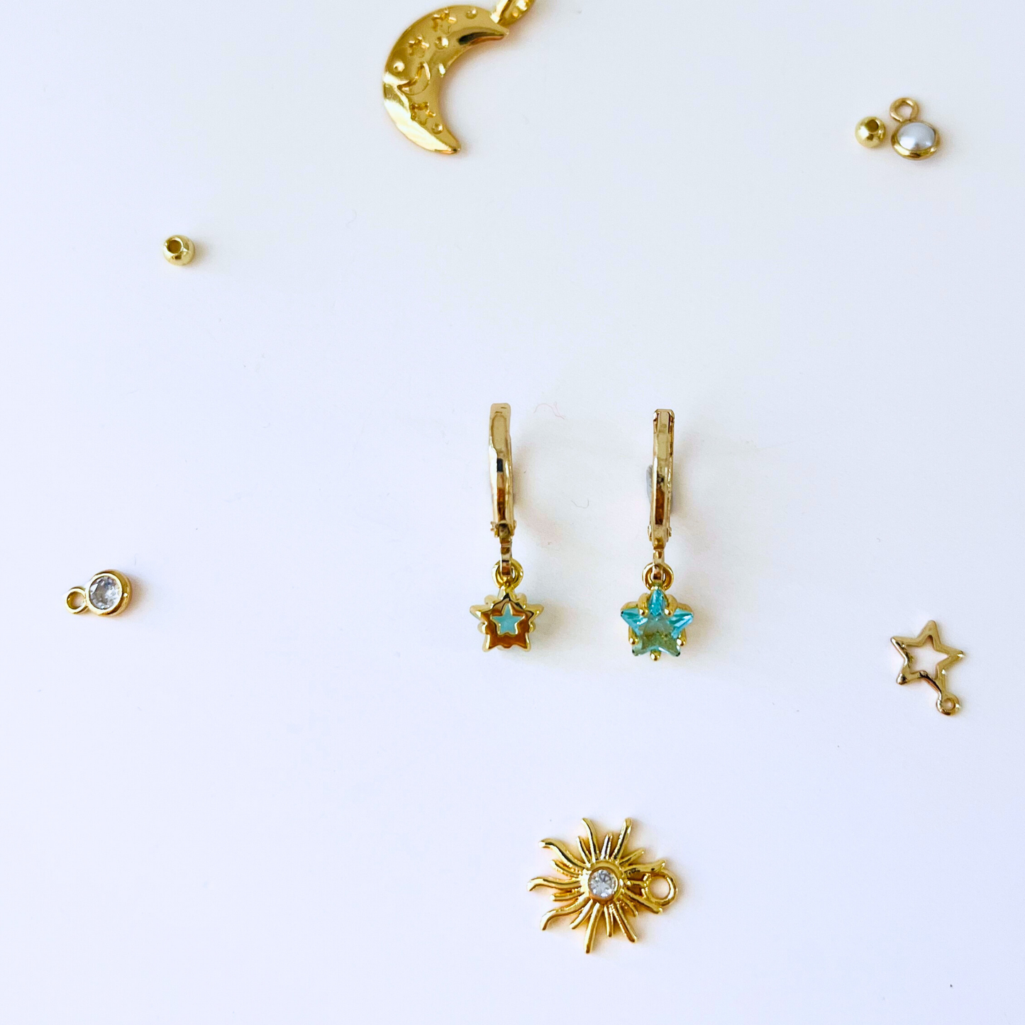 Collection of gold earrings with star and moon designs on a white background