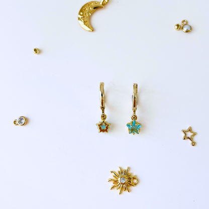 Collection of gold earrings with star and moon designs on a white background