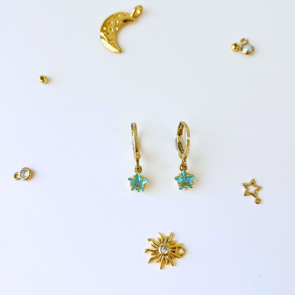 Collection of gold earrings with star, moon, and sun designs on a white background