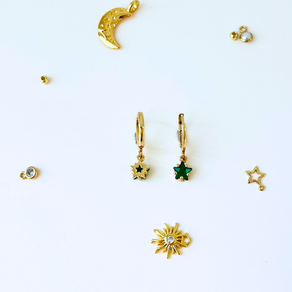 Gold earrings with star and moon designs on a white background