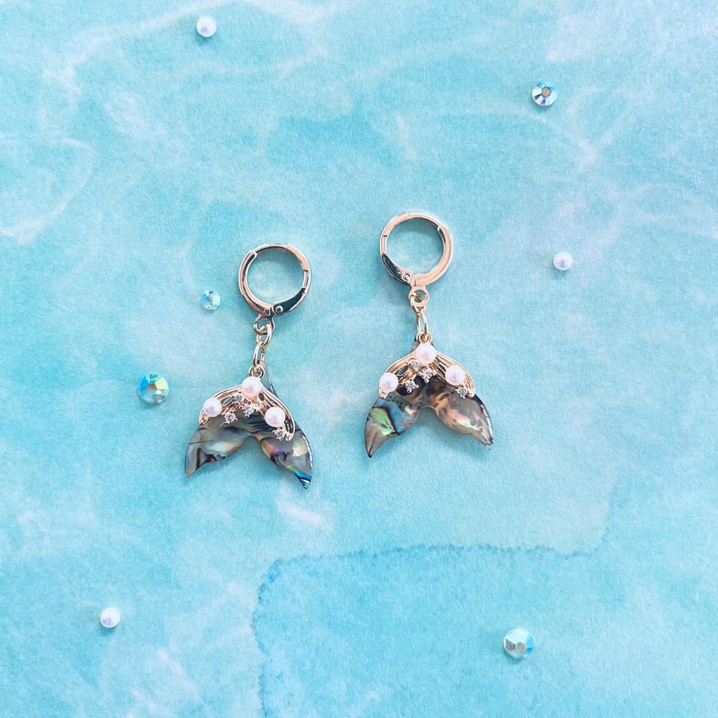 Pair of Mermaid Tail Earrings on a blue water textured background