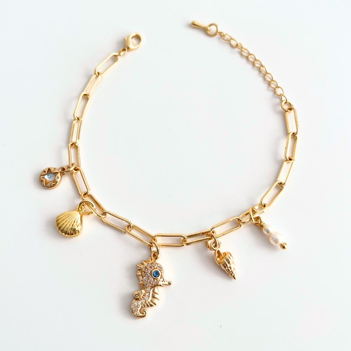 Gold bracelet with seahorse, shell, pearl ocean theme charms on a light background