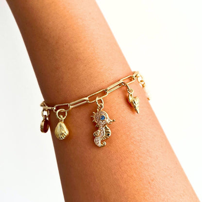 Gold Plated Ocean Charm Shell Pearl  Seahorse bracelet on a wrist against a white background