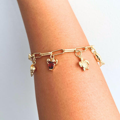Gold plated Sea creatures bracelet with various charms on a wrist against a light background