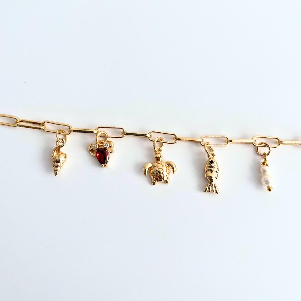 Gold plated Sea creatures bracelet with various charms on a white background