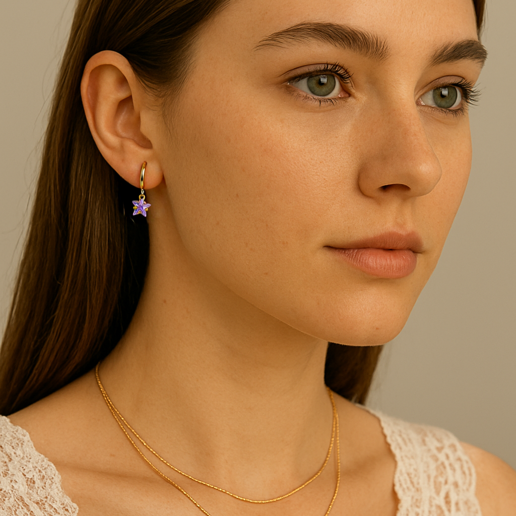 Woman wearing gold necklaces and a purple earring against a neutral background